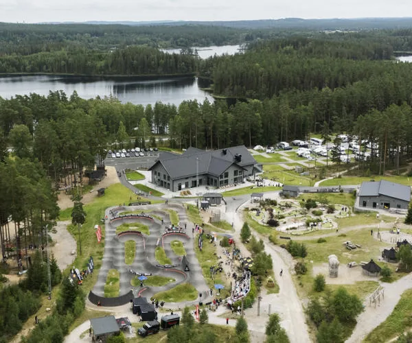 Flygbild över pumptracken och teknikområdet vid Isaberg, omgivna av skog och sjöar
